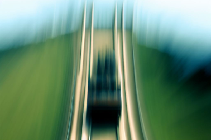 A blurry view of a rollercoaster coming down the tracks directly at us.